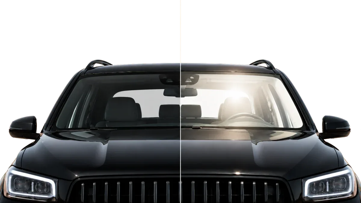 Front view of a vehicle windshield split down the middle: ceramic window tint on the left with a cool, glare-free interior, and untinted glass on the right with harsh Arizona sun glare.